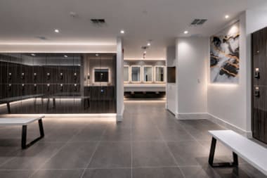 Sleek locker room with dark lockers, gray tile floor, and white benches.