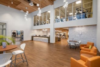 Modern health club lobby with wood floors, lounge chairs, and reception desk.