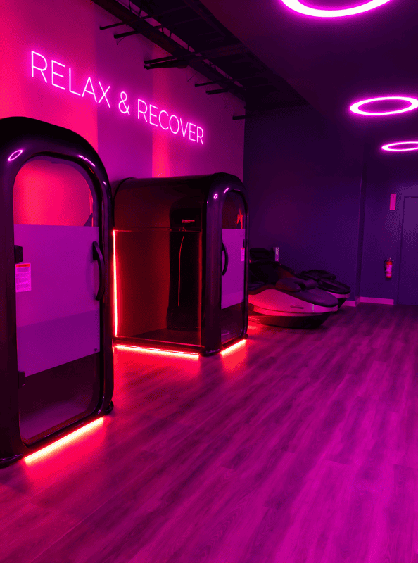 Recovery space design of Longfellow Lumina Studio with recovery pods, LED baseboards, neon lighting, and circular ceiling lights