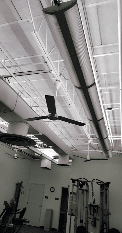 Exercise space design of Longfellow Lumina Studio before renovation with exposed ceiling and suspended linear lighting.