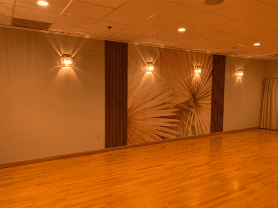 Barre room design of Longfellow Lumina Studio after renovation with wall mural, wood slats, and warm lighting.