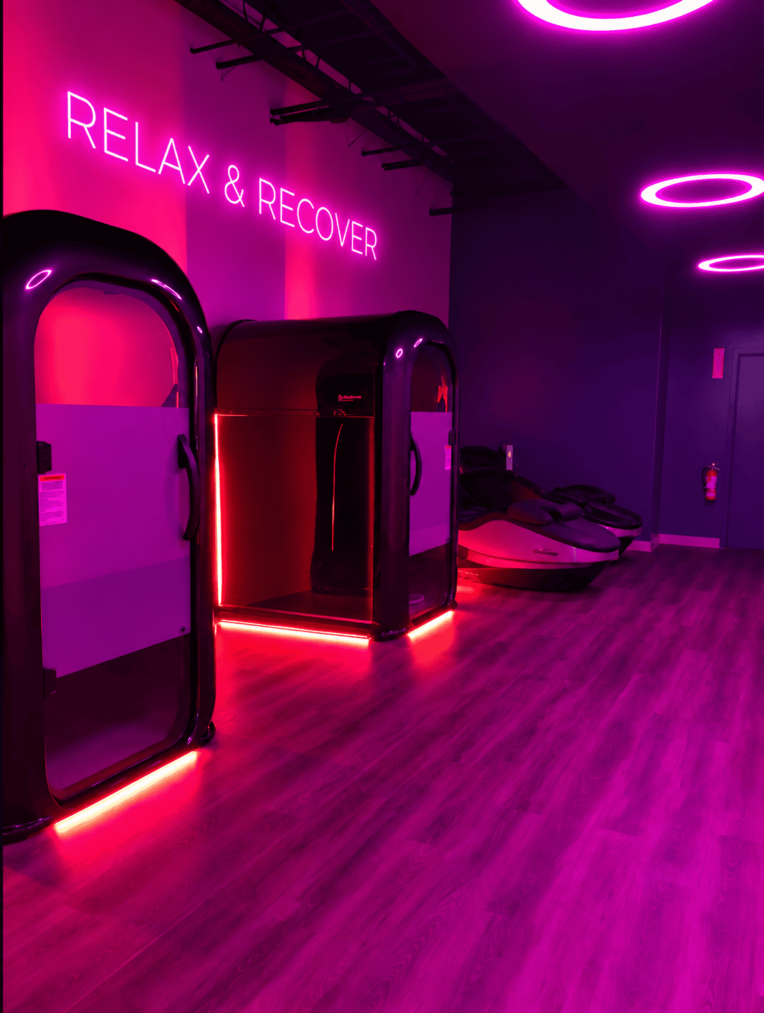 Recovery space design of Longfellow Lumina Studio with recovery pods, LED baseboards, neon lighting, and circular ceiling lights